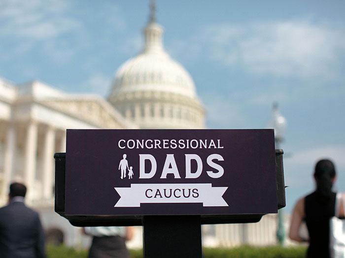 Congressional Dads Caucus sign on podium in front of U.S. Capitol